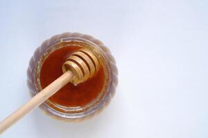 spoon in a glass jar of honey on a white background. photo