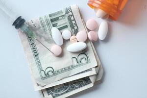 Stack of cash dollars , pills and syringe on white background photo