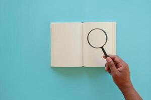 open book and magnifying glass on table. photo