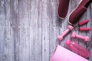 Mancuerna de color rosa, zapatos y auriculares sobre fondo rosa foto
