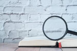 Close up of magnifying glass on book on table photo