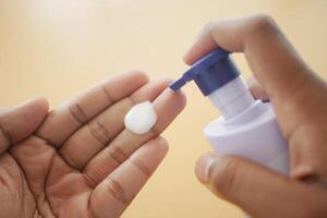 Close up of pouring moisturizing cream on hand photo