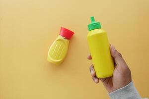 holding a bottle of mustard mayonnaise on yellow background photo