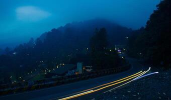 colorful night light trails on road with forest background in puncak bogor Indonesia photo