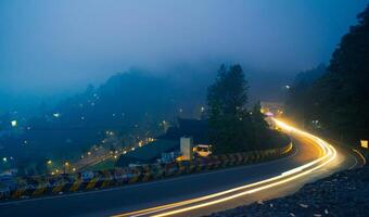 colorful night light trails on road with forest background in puncak bogor Indonesia photo