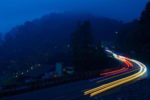 vistoso noche ligero caminos en la carretera con bosque antecedentes en puncak bogor Indonesia foto