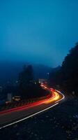 colorful night light trails on road with forest background in puncak bogor Indonesia photo