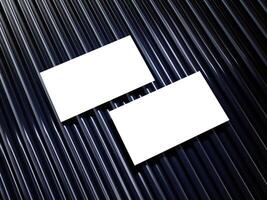 Closeup of empty white rectangle business card mockups lying diagonally on metallic blue background. Flat lay, top view. Open composition. Blank Template for Corporate Identity. Copy space. photo