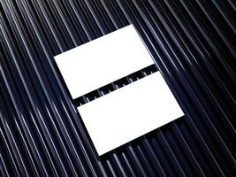 Closeup of empty white rectangle business card mockups lying diagonally on metallic blue background. Flat lay, top view. Open composition. Blank Template for Corporate Identity. Copy space. photo