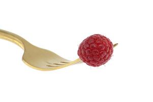 Fresh raspberry on gold fork isolated on white background photo