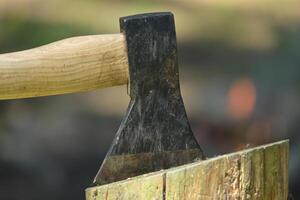 de cerca ver de hacha con de madera encargarse de incrustado en un Iniciar sesión de madera foto