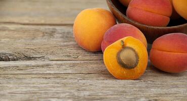 Group of fresh apricots isolated on rustic wooden table photo