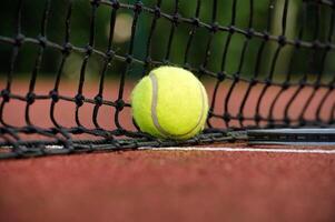 Yellow tennis ball near white line and black net photo