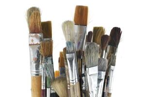 Array of paintbrushes of different sizes and colors over white photo