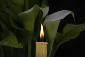Burning wax candle in close up and white calla lily photo
