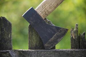 Detailed view of axe lodged into an old, weathered wooden fence photo