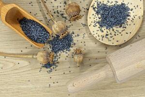 Poppy seeds and several dried poppy seed pods on wooden table photo