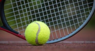 Tennis ball and racket lying on tennis hard court photo