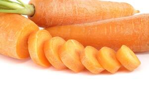 Whole carrot and its sliced pieces isolated against a white background photo