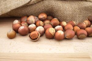 Hazelnuts beside the jute sack on wooden table photo