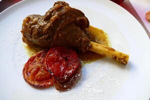 Lamb shank and grilled tomato for lunch photo