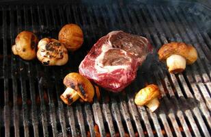 Rib eye steak and mushrooms on the grill photo