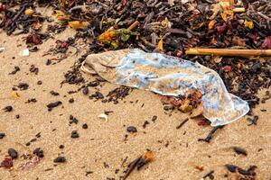 condom on the seashore closeup top view. ecological problems photo