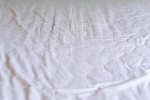 Crumpled or wrinkled white bedding sheet background texture taken with soft natural light used for clothing background texture photo