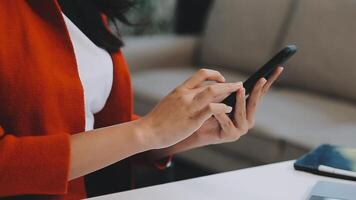 Asian woman entrepreneur busy with her work in the office. Young Asian woman work on desk laptop phone while planning sales, research or financial strategy in company video