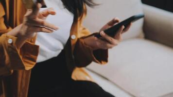 Asian woman entrepreneur busy with her work in the office. Young Asian woman work on desk laptop phone while planning sales, research or financial strategy in company video