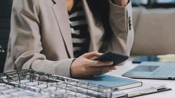 Asian woman entrepreneur busy with her work in the office. Young Asian woman work on desk laptop phone while planning sales, research or financial strategy in company video