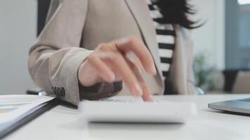 Asian Businesswoman Using laptop computer and working at office with calculator document on desk, doing planning analyzing the financial report, business plan investment, finance analysis concept. video