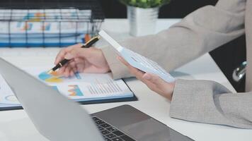 Asian Businesswoman Using laptop computer and working at office with calculator document on desk, doing planning analyzing the financial report, business plan investment, finance analysis concept. video