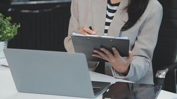 Asian Businesswoman Using laptop computer and working at office with calculator document on desk, doing planning analyzing the financial report, business plan investment, finance analysis concept. video