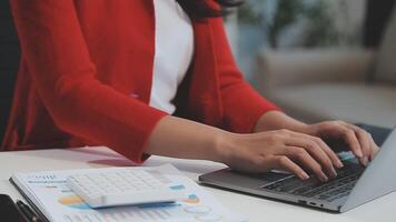 Asian Businesswoman Using laptop computer and working at office with calculator document on desk, doing planning analyzing the financial report, business plan investment, finance analysis concept. video