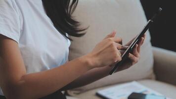 Asian woman entrepreneur busy with her work in the office. Young Asian woman work on desk laptop phone while planning sales, research or financial strategy in company video