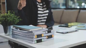 mujer de negocios asiática que usa una computadora portátil y trabaja en la oficina con un documento de calculadora en el escritorio, planificando el análisis del informe financiero, la inversión del plan de negocios, el concepto de análisis financiero. video