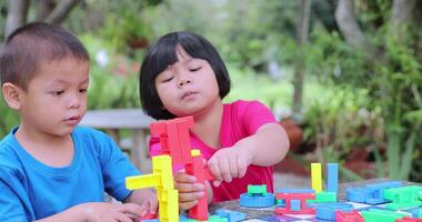 een meisje en een broer zijn spelen met plastic puzzels. video