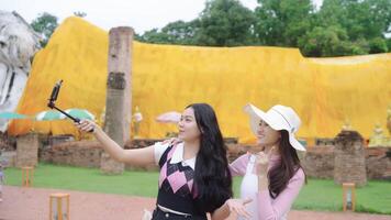 Two Asian women backpack are bloggers vlog creating temple travel content in Ayutthaya. Have fun, smile during holidays. video