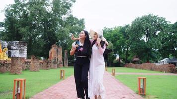 Two Asian women are backpackers traveling. at a Buddhist temple Ayutthaya in Thailand Lifestyle is that tourists look very happy. Smile and have fun while on vacation. video