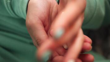 Female hands close-up in this as fingers take pills from the palm. The green color of clothes and nails highlights the scene, focusing on the act of picking up and holding the pills. video