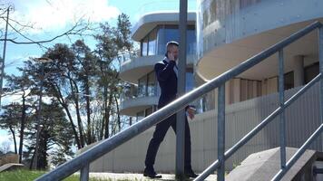 gekleed scherp in bedrijf kleding, een zakenman praat Aan zijn telefoon terwijl staand Aan een stad straat met een kantoor gebouw backdrop zakenman wisselwerking betekent: dringend bedrijf communicatie video