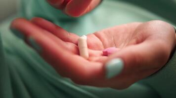 female hands with green nails and clothes throwing pills from one hand to another and then covering pills with a fist movement emphasizes the handling and control of pills throughout the sequence. video