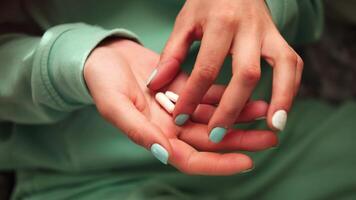 esta imágenes caracteristicas hembra manos de cerca, con dedos seleccionando pastillas desde el palmera. el verde color de ropa y uñas mejora el visual impacto, centrado en el Interacción con el pastillas video