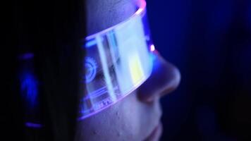 ervaring de snijdend rand van technologie net zo een jong vrouw dompelt zich onder haarzelf in virtueel realiteit, haar virtueel realiteit bril versierd met een boeiend neon gloed, verhelderend de digitaal rijk video