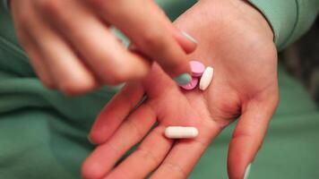 esta muestra De las mujeres manos con verde uñas y en ropa dedos son considerado pastillas en el palma de su manos. el movimiento enfatiza el Interacción con el pastillas salud concepto video