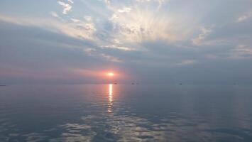 A ship in the sea is silhouetted against a sunrise. Morning in the oilfield. photo