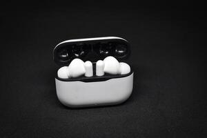 White Wireless earphones, earbuds on a dark background photo