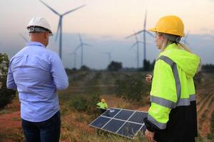 Chief engineer audits job progress at site line of energy construction, business discussion. Wind turbine and solar cell project at windmill photo