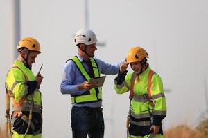 Specialist wind turbine Team of Engineers discussing Green Energy Production in Wind Turbines Farm or Windmills Field. Team of Engineer Energy Planning Activity in Windmills Industrial Area photo